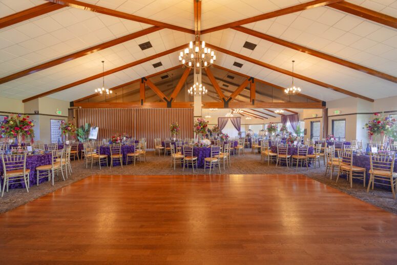Elegant indoor wedding reception ballroom with round tables and hardwood floors at Bonita Golf Course.