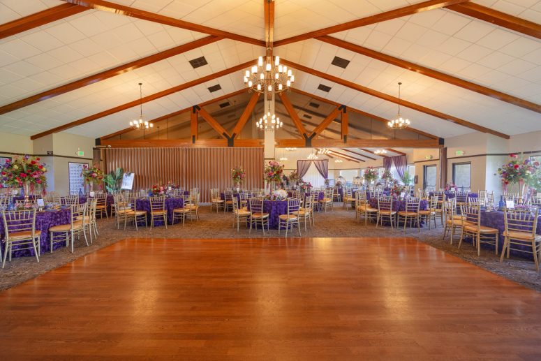 Elegant indoor wedding reception ballroom with round tables and hardwood floors at Bonita Golf Course.